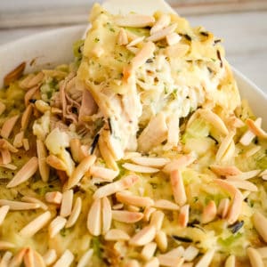 chicken and wild rice casserole being spooned out of a casserole dish