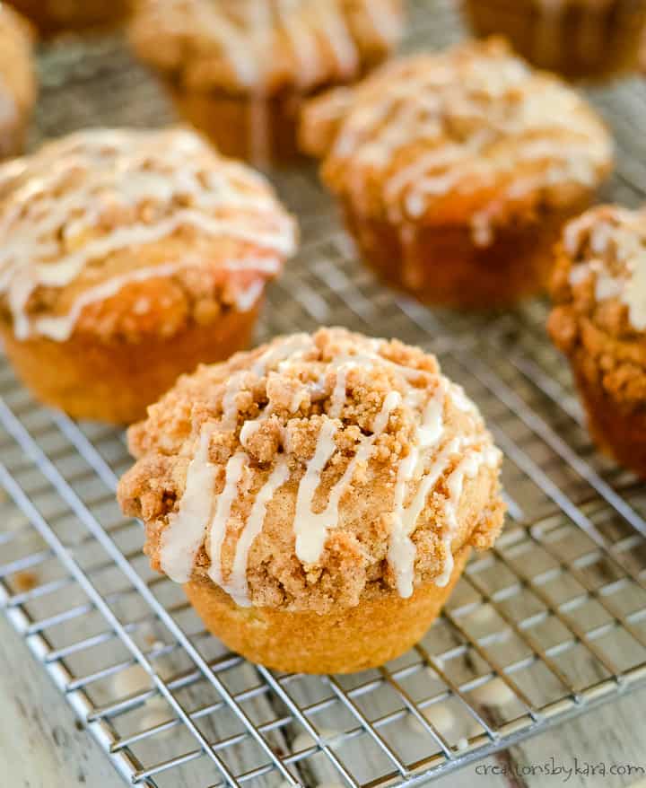 icing dripping off of apple muffins with crumble topping.