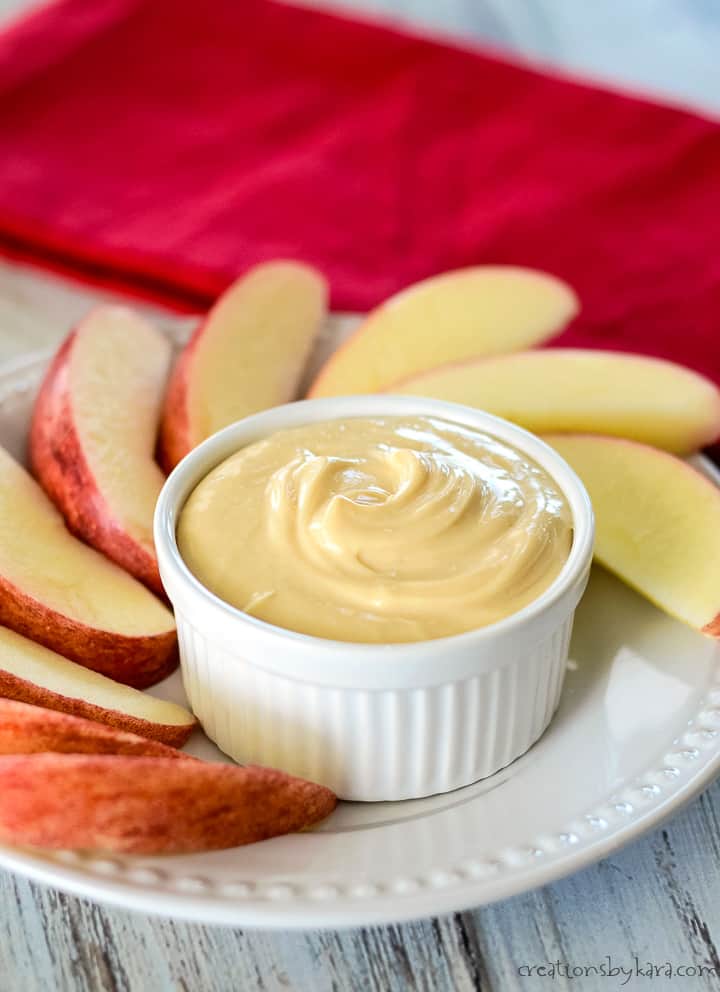 bowl of dip on a plate with sliced apples