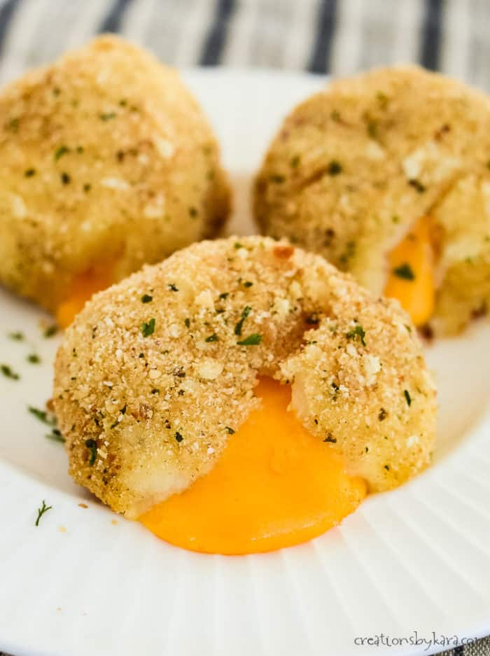 overhead shot of cheesy baked potato balls on a white plate.