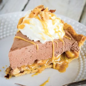 slice of chocolate turtle pie with whipped cream, caramel, and salted peanuts