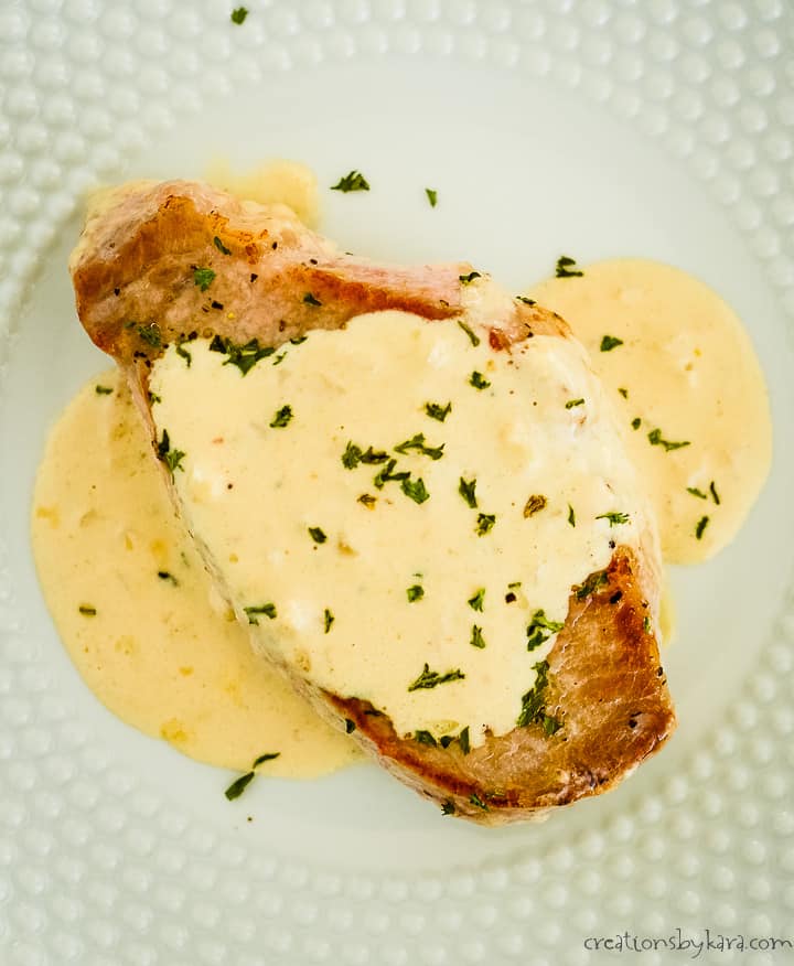 overhead shot of pork chop on a plate covered with creamy garlic sauce