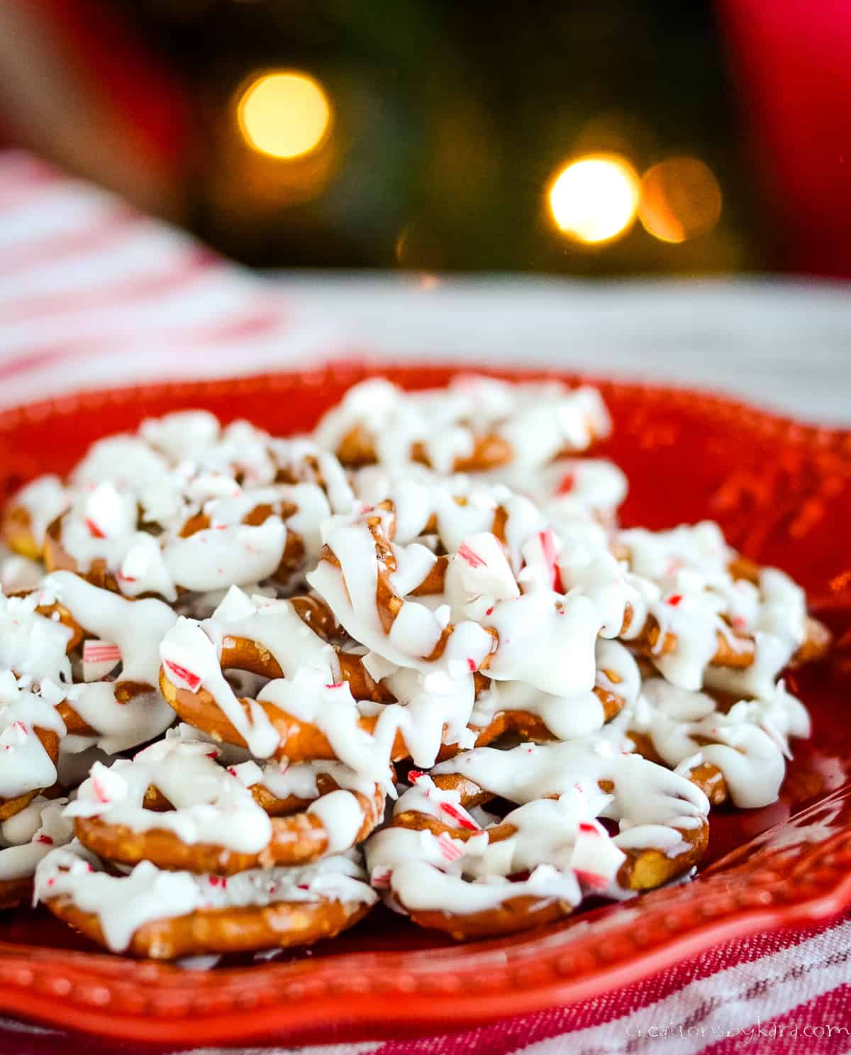 white chocolate peppermint pretzels on a red plate with a striped tea towel