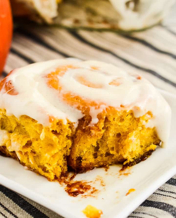 pumpkin cinnamon roll on a plate with a bite taken out of it