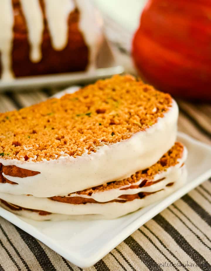 two slices of zucchini pumpkin bread with cinnamon icing on a white plate