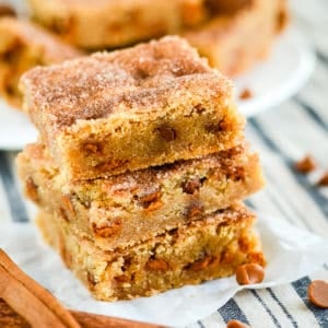 snickerdoodle bars in a stack with cinnamon sticks in the foreground