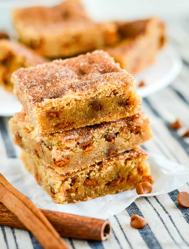 snickerdoodle bars in a stack with cinnamon sticks in the foreground