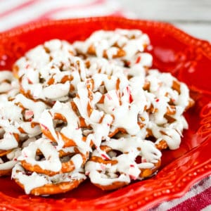 white chocolate covered pretzels with crushed candy cane on a red plate