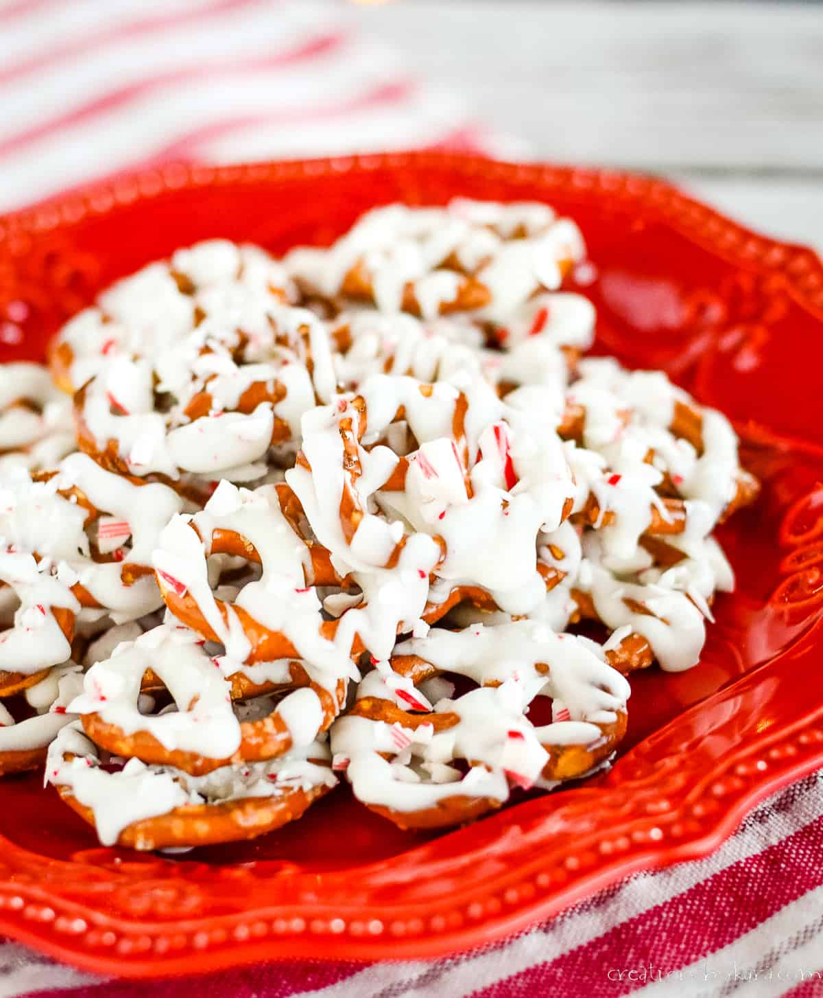 white chocolate covered pretzels with crushed candy cane on a red plate