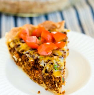 slice of cheeseburger pie garnished with diced tomatoes