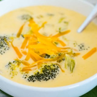 bowl of keto cheddar broccoli soup garnished with shredded cheese
