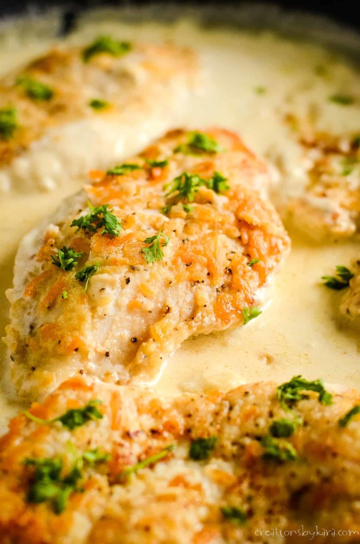 skillet of chicken with garlic sauce garnished with parsley