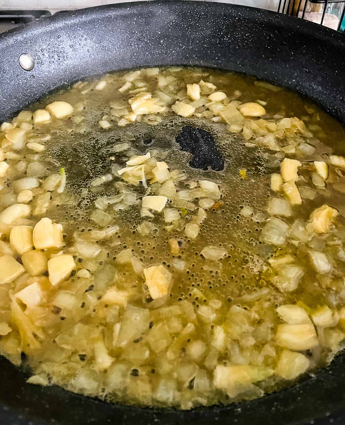 onion, garlic, and chicken bouillon simmering in a skillet