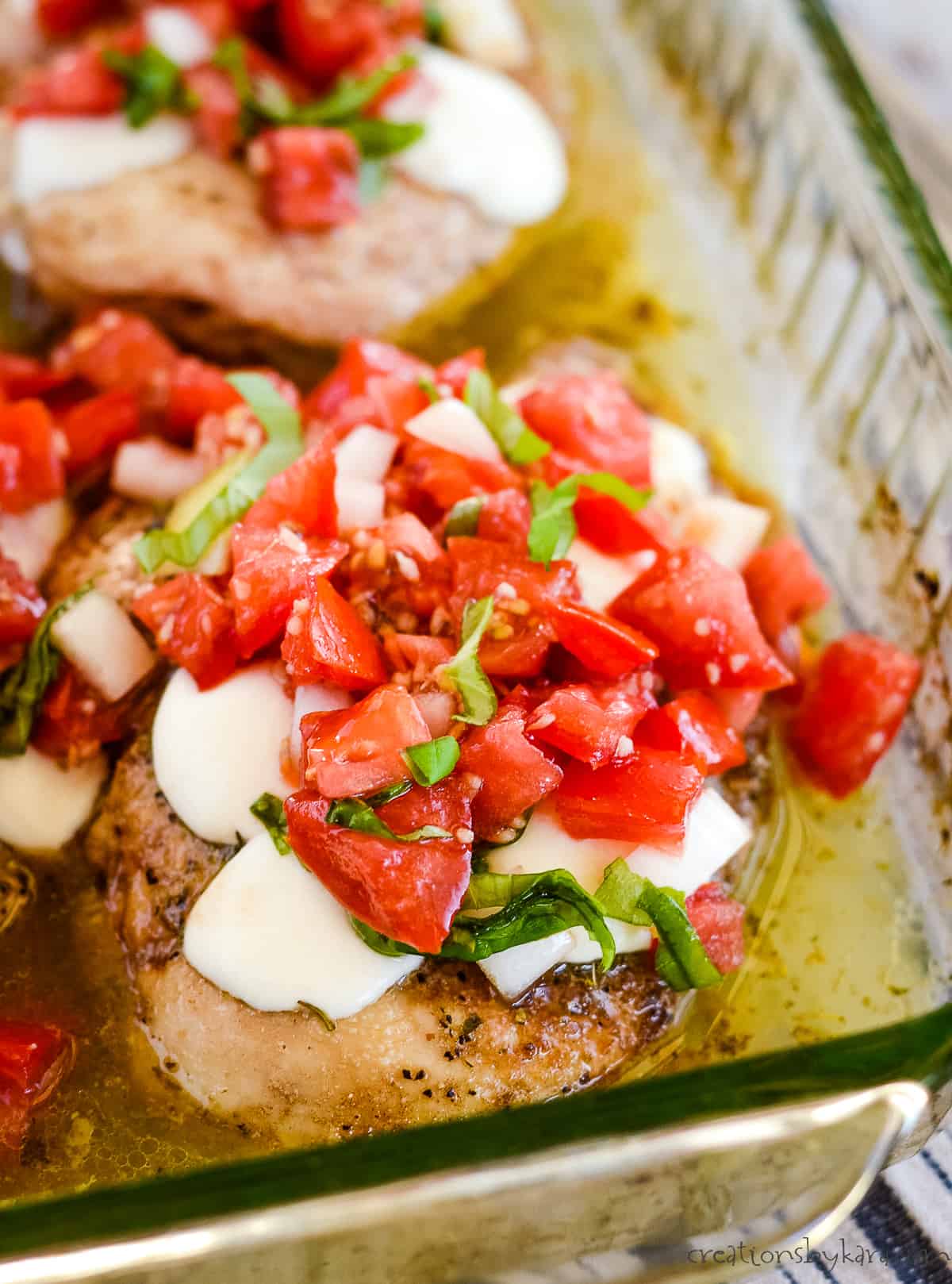 baked bruschetta chicken in a glass dish topped with mozzarella cheese