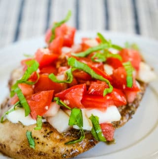 plate with baked chicken bruschetta topped with mozzarella and fresh basil