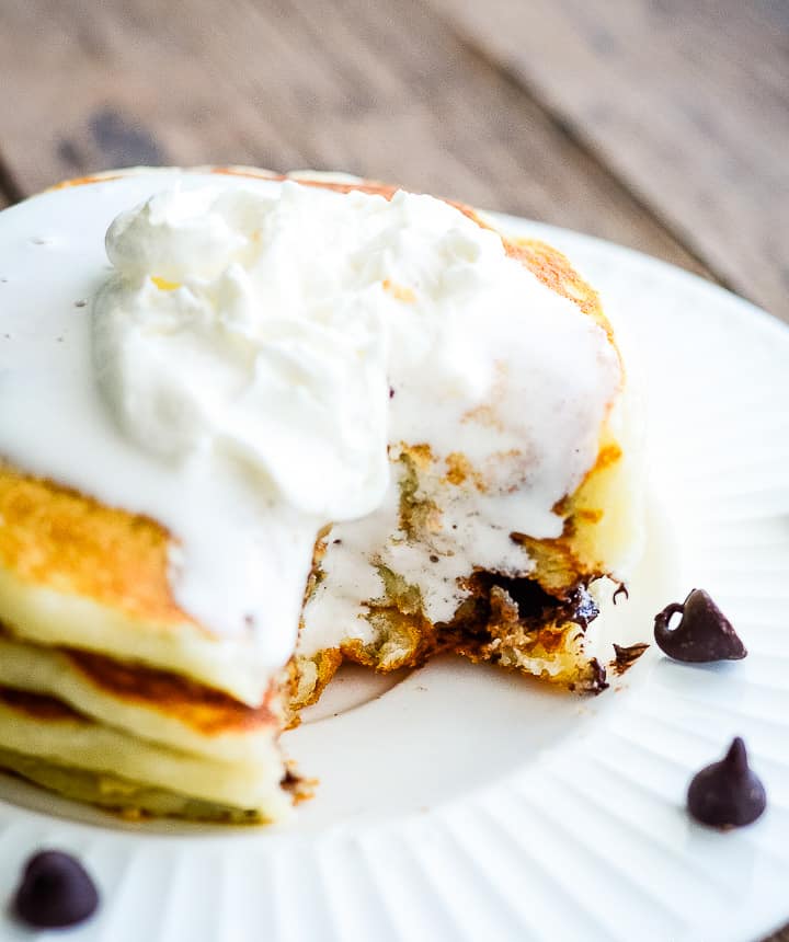 plate of chocolate chip pancakes topped with whipped cream