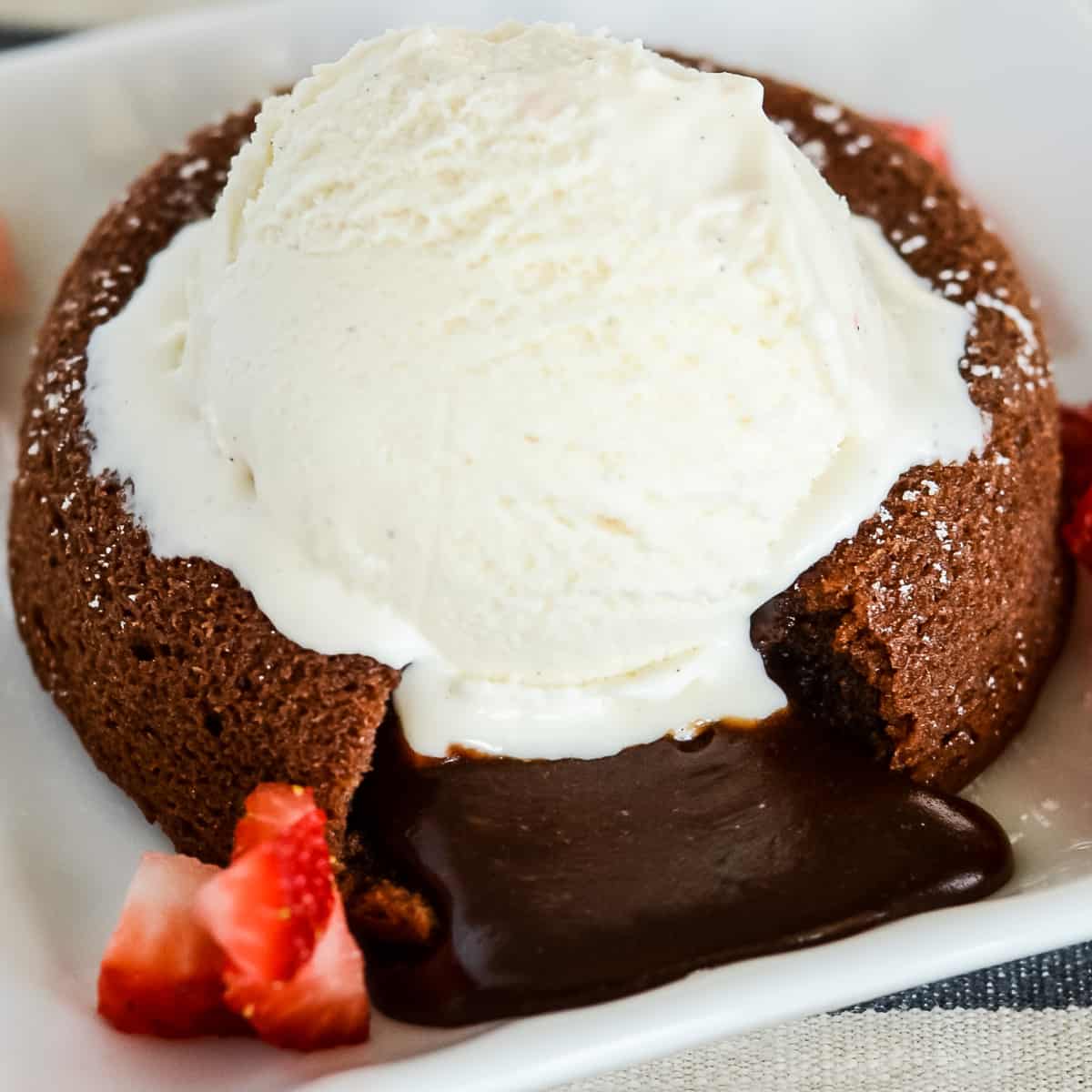 Warm chocolate lava cake topped with vanilla ice cream and strawberries