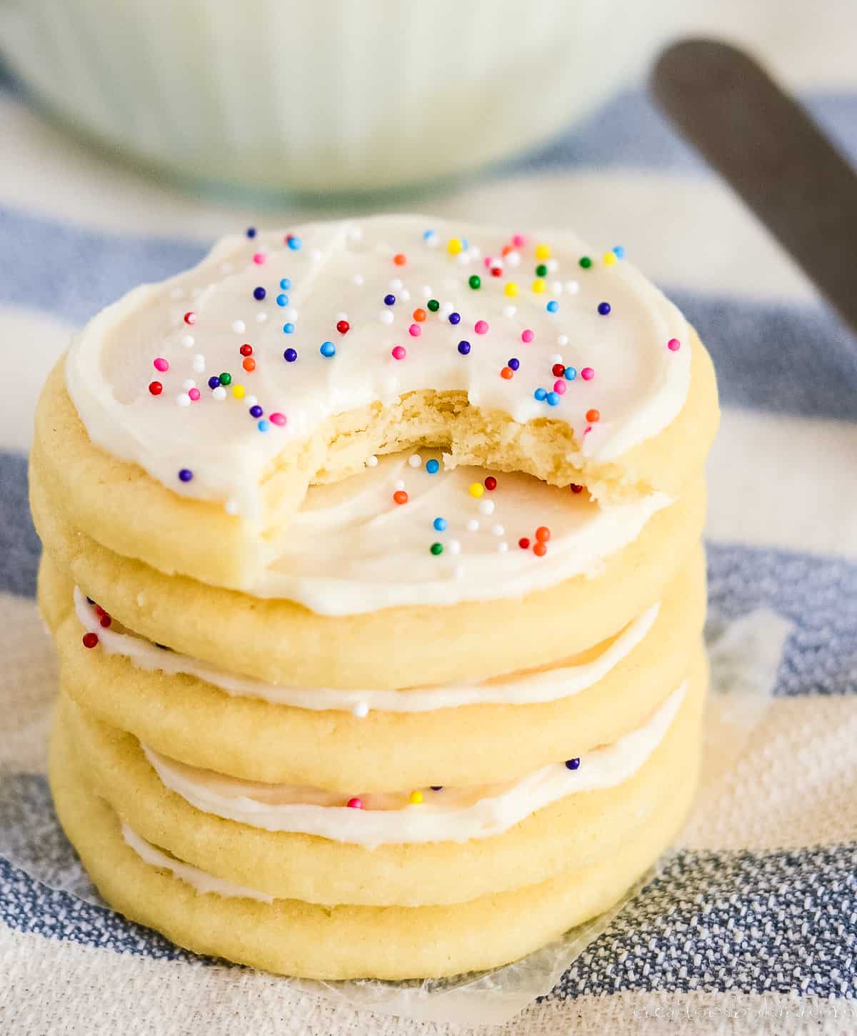 stack of sugar cookies with frosting and sprinkles