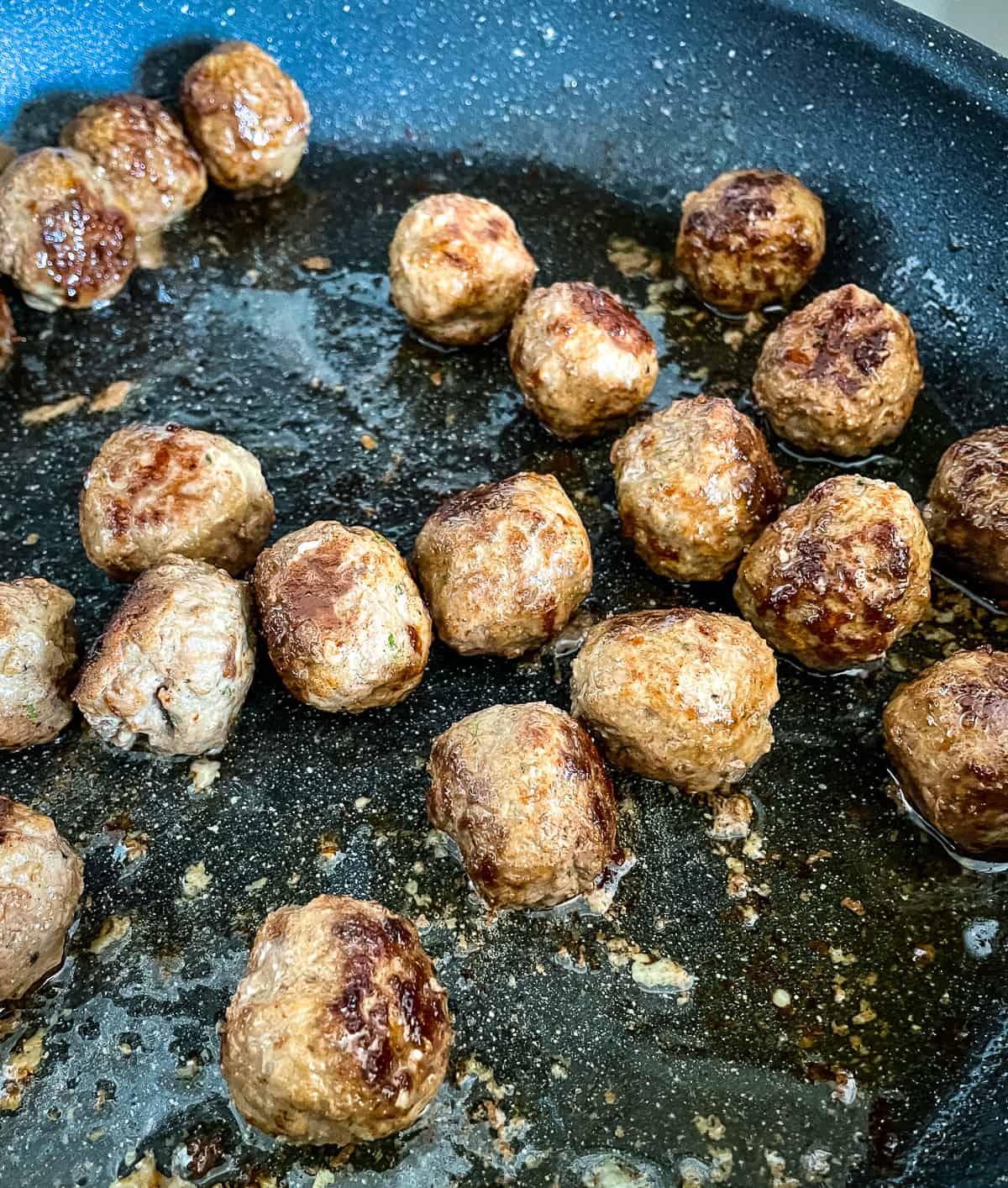 meatballs being browned in a skillet