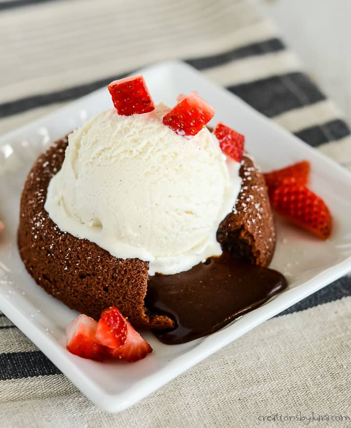 Plate with molten lava cake topped with vanilla ice cream and diced strawberries