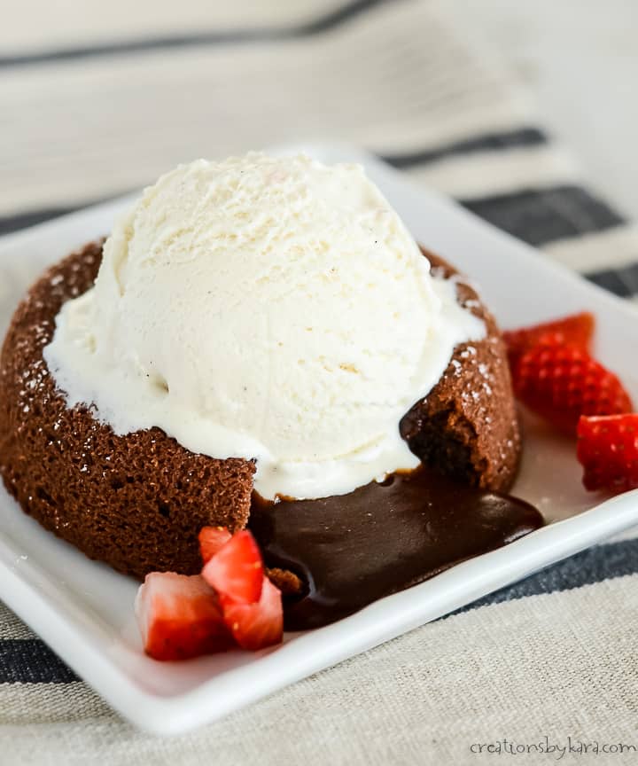 plate with chocolate molten lava cake topped with vanilla ice cream and strawberries