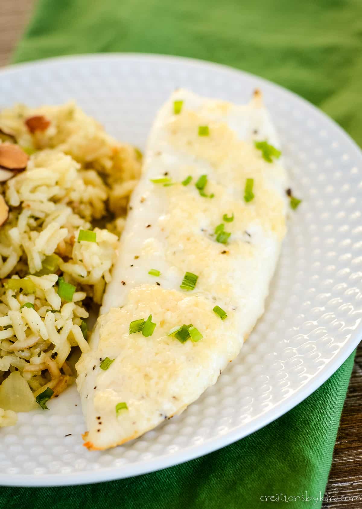 piece of broiled tilapia on a plate with a side of rice pilaf