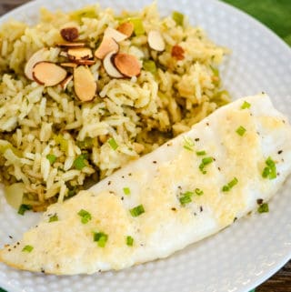 overhead shot of plate of broiled tilapia parmesan with rice pilaf