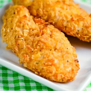 close up of crispy cornflake chicken tenders on a white plate