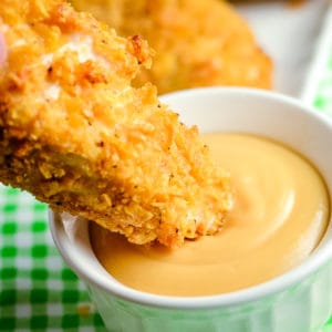 baked chicken strips, one being dipped in sauce