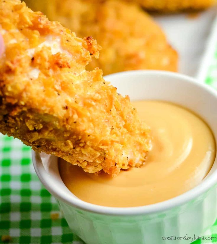 baked chicken strips, one being dipped in sauce