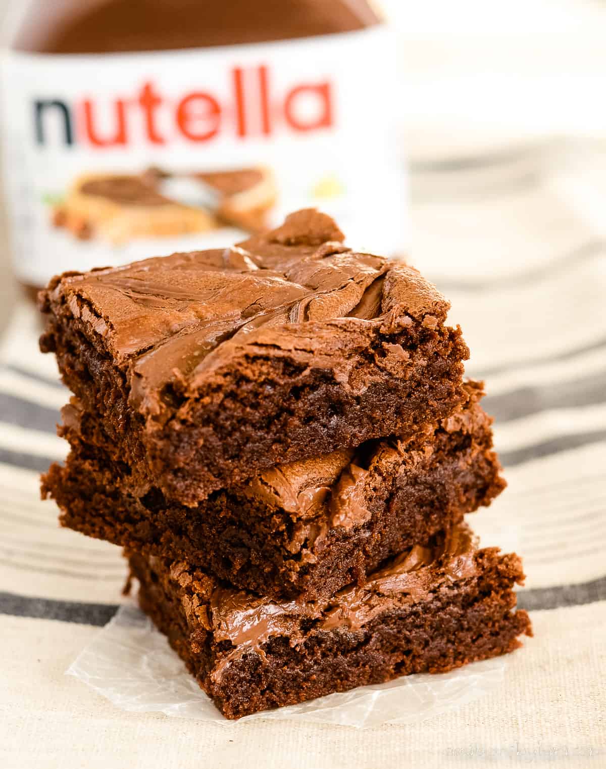 stack of nutella brownies with a jar of chocolate hazelnut spread in the background