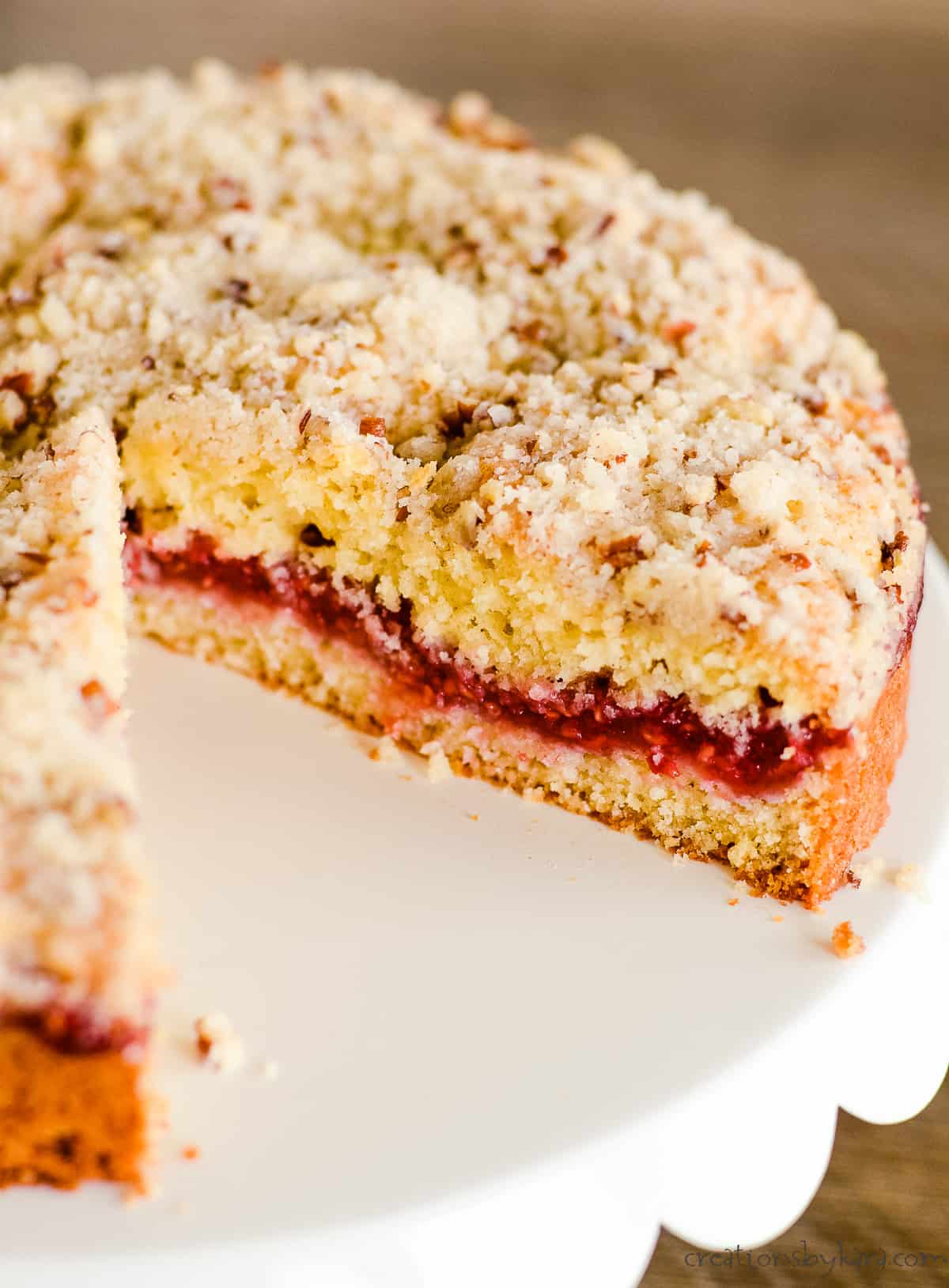 sliced coffee cake with raspberries on a white cake stand