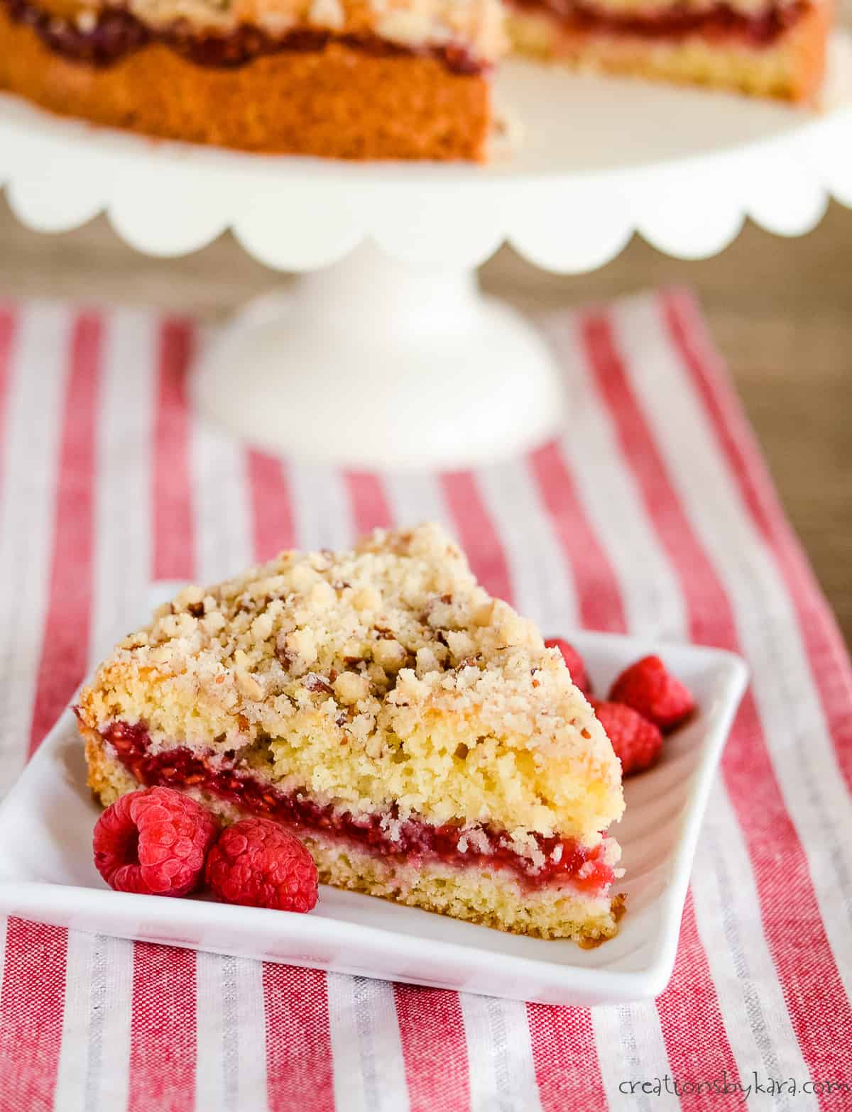 slice of raspberry filled coffee cake on a plate with a cake in the background