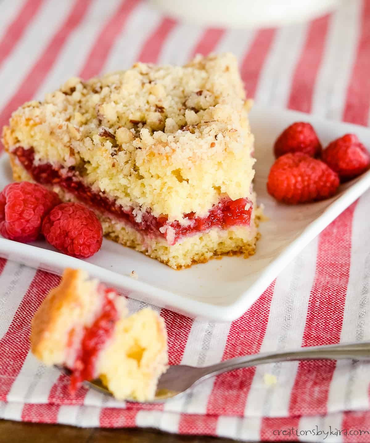 raspberry coffee cake on a plate with a bite taken out of it