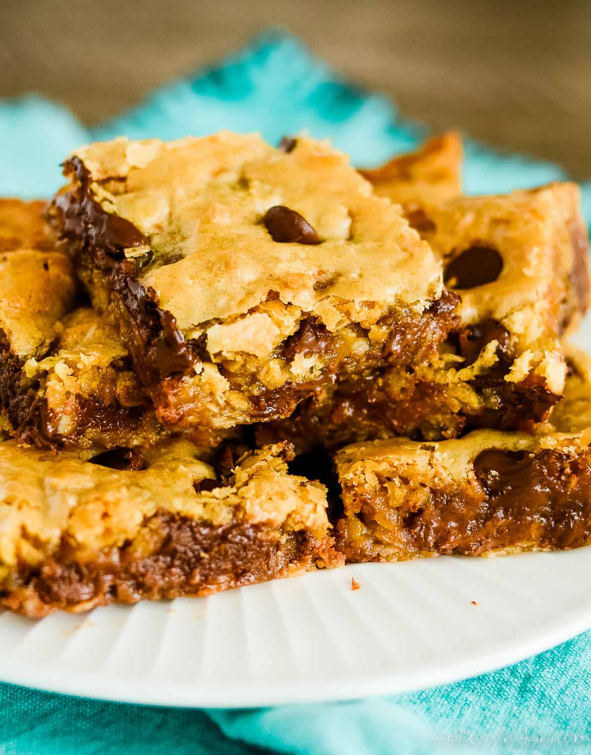 plate of warm and gooey chocolate chip oatmeal bars on a blue fabric napkin