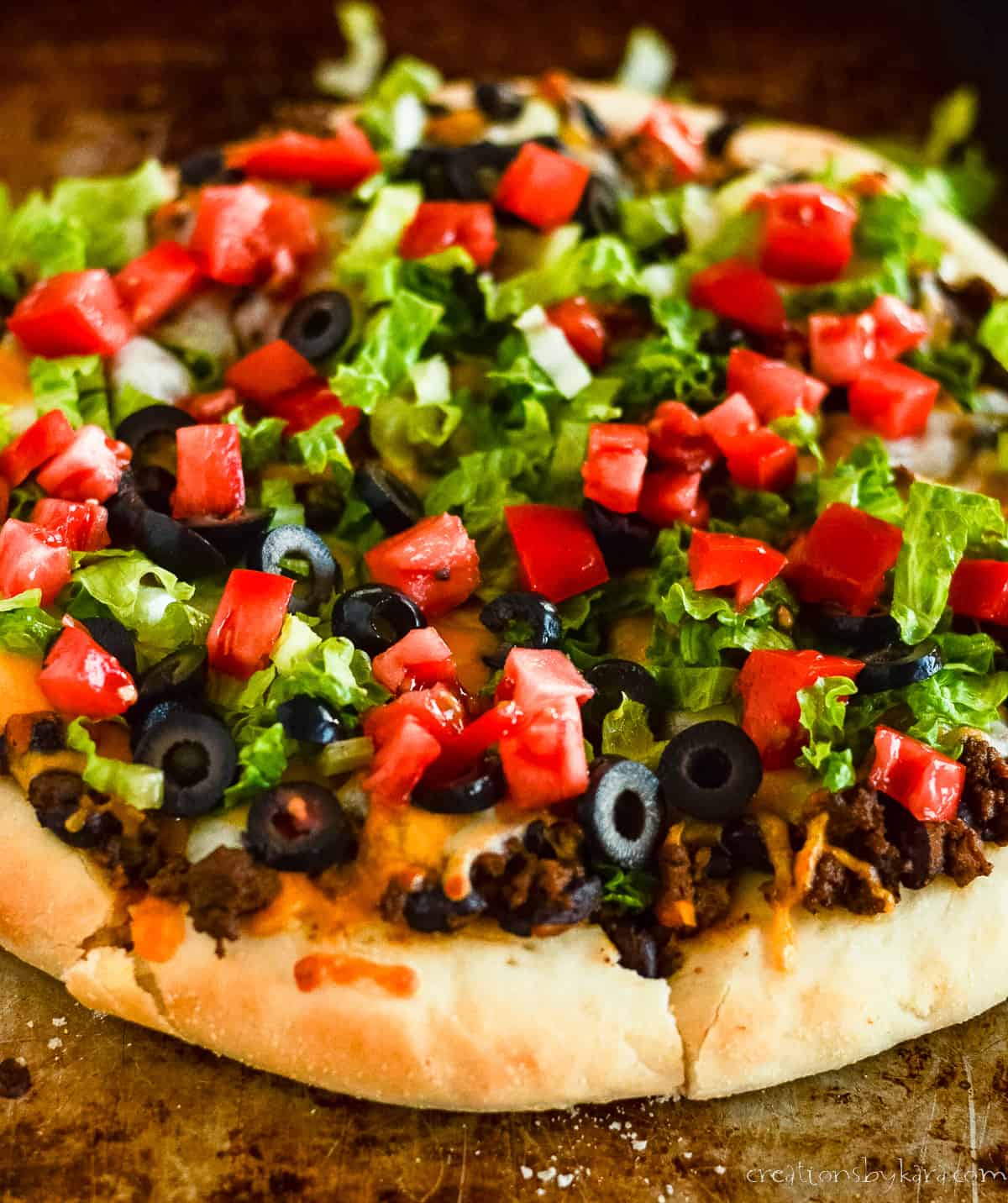 whole pizza with ground beef, cheese, lettuce, and diced tomato