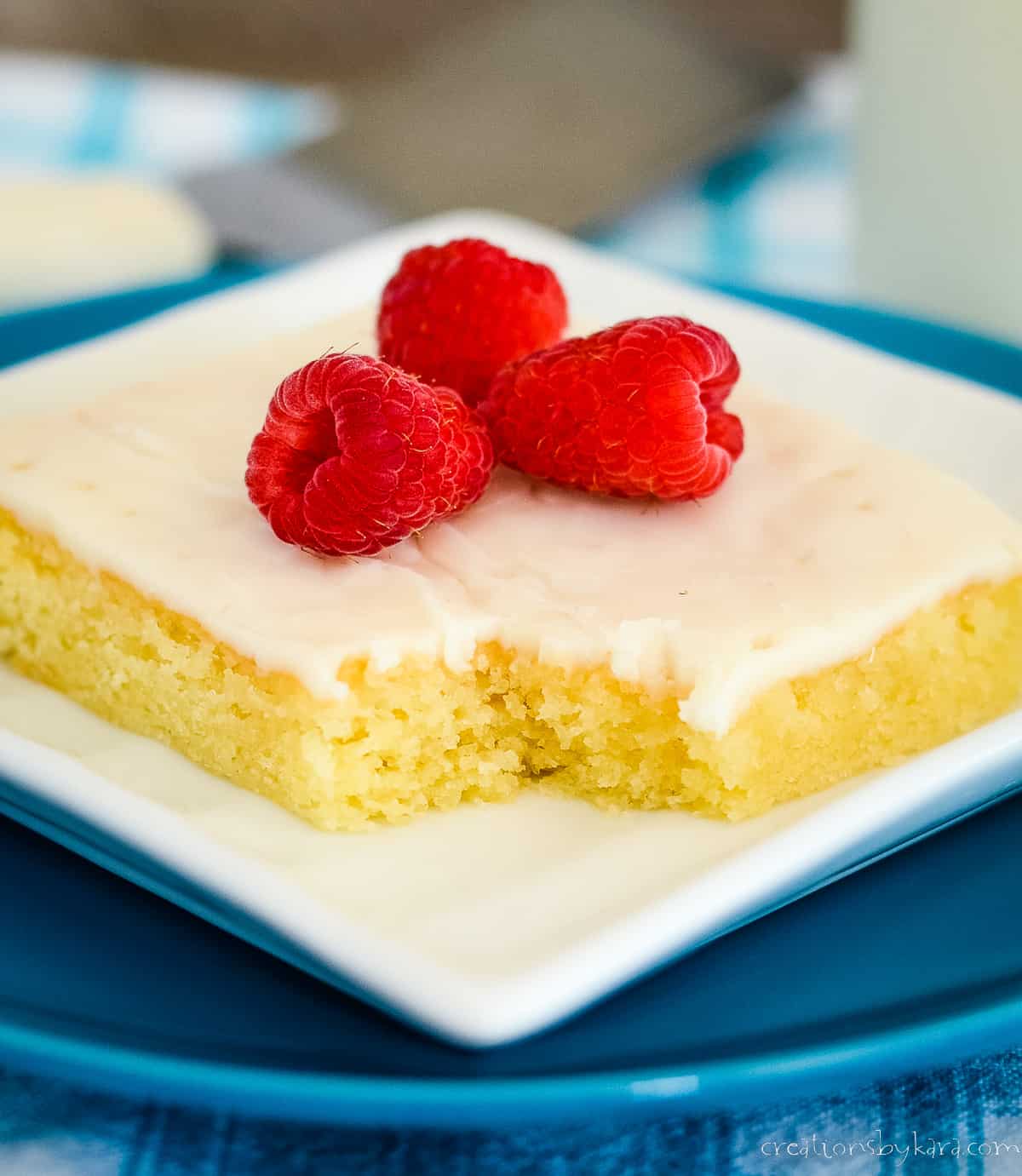 slice of almond sheet cake topped with fresh raspberries