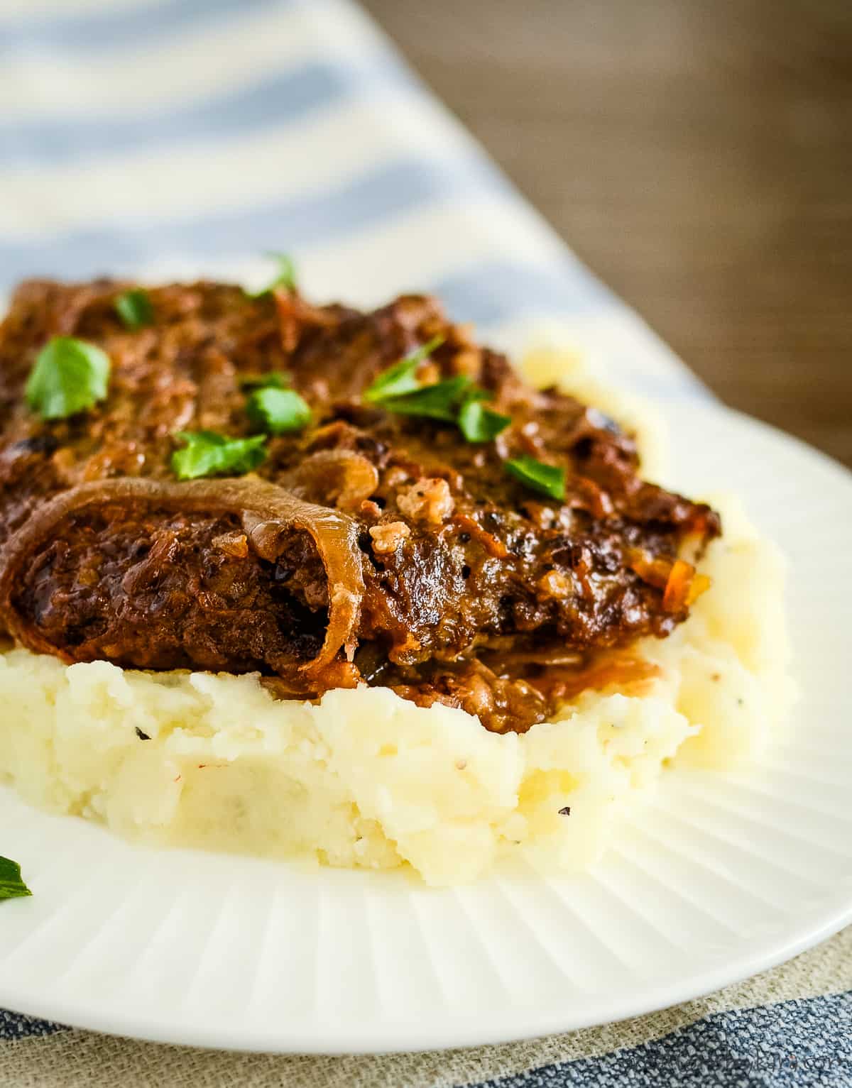 plate of mashed potatoes, cube steak, and gravy, garnished with parsley