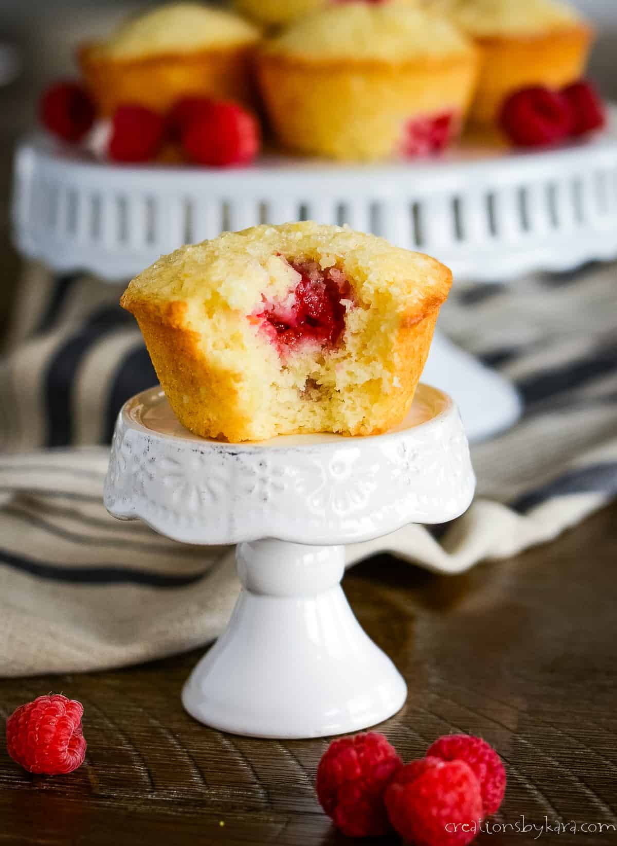 lemon raspberry muffin on a cupcake stand with more muffins in the background