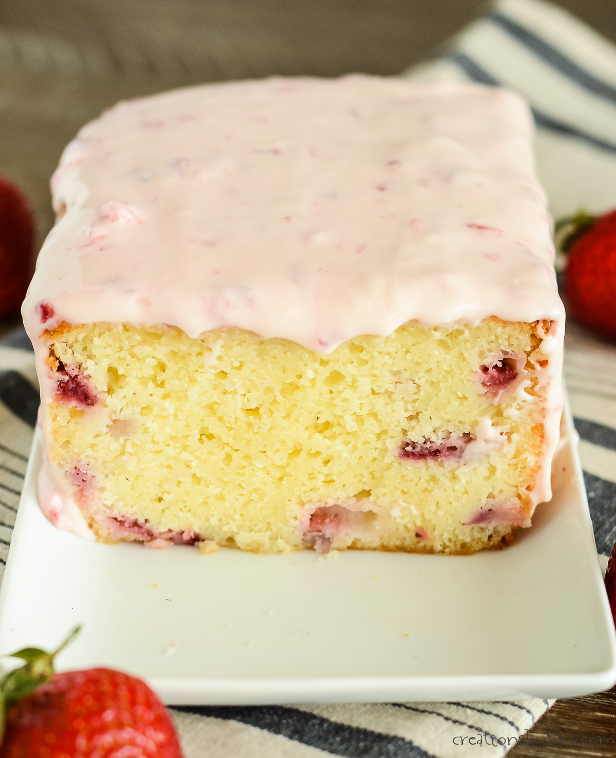 loaf of sliced strawberry pound cake with cream cheese strawberry glaze