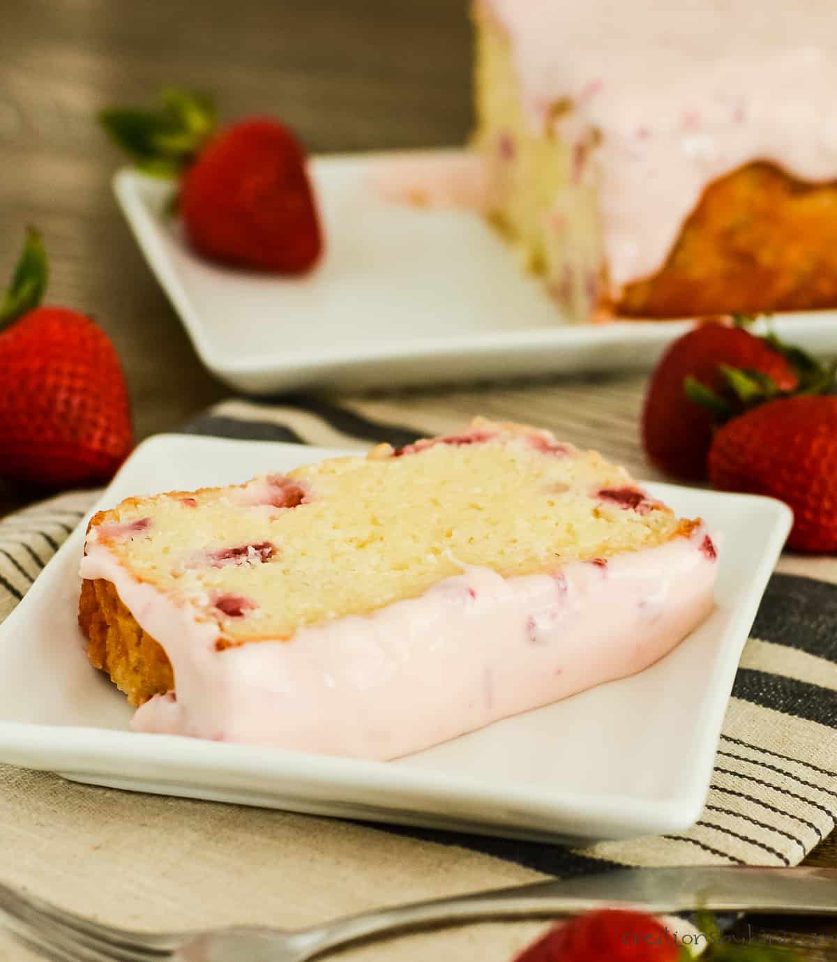slice of strawberry pound cake on a plate with a cut cake in the background