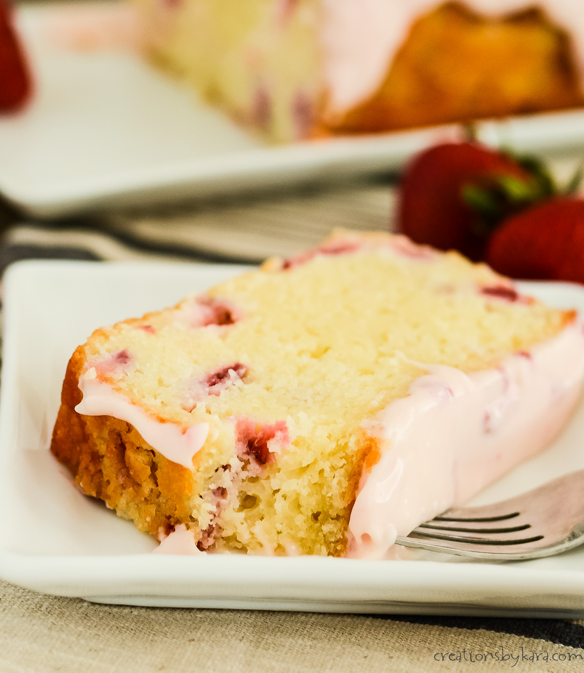 plate with a slice of strawberry pound cake with a fork and a bite taken out of it.
