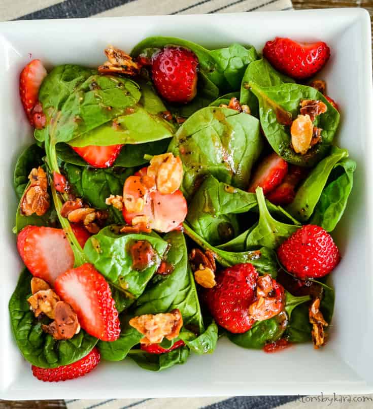overhead shot of spinach salad with strawberries, candied almonds, and strawberry vinaigrette