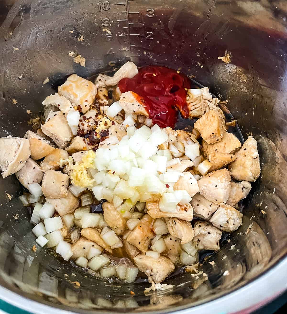 chicken and sauce ingredients in the bottom of an instapot