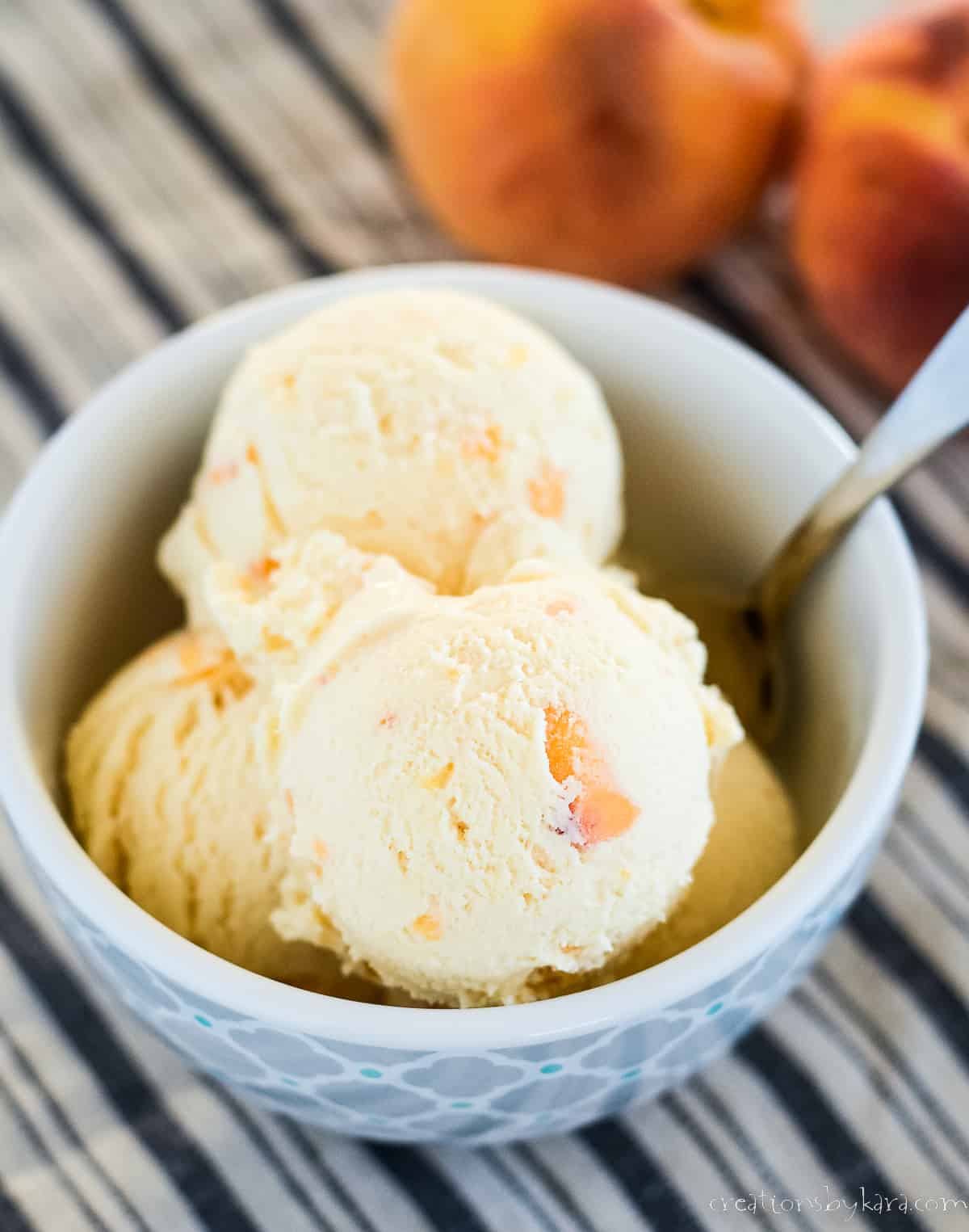 bowl of fresh peach ice cream with peaches in the background