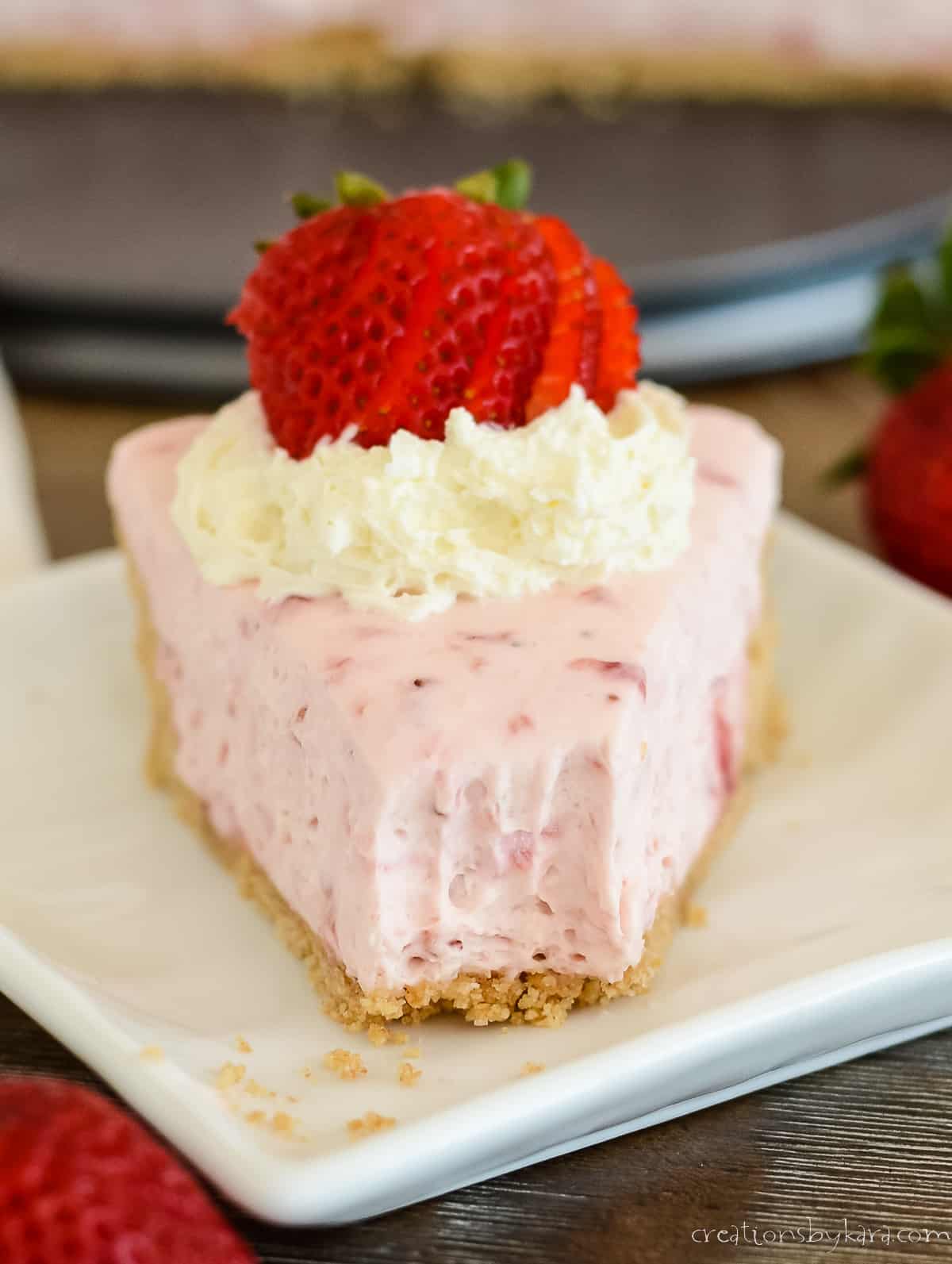 close up of plate with a slice of no bake cheesecake with strawberries with a bite taken out of it
