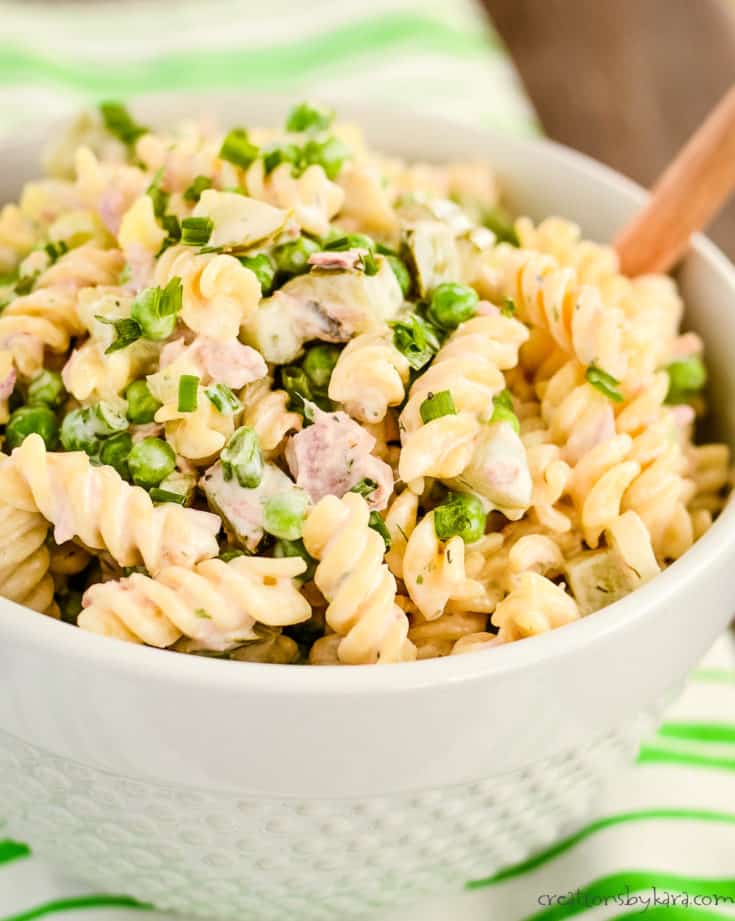 macaroni tuna salad in a white bowl with a wooden spoon