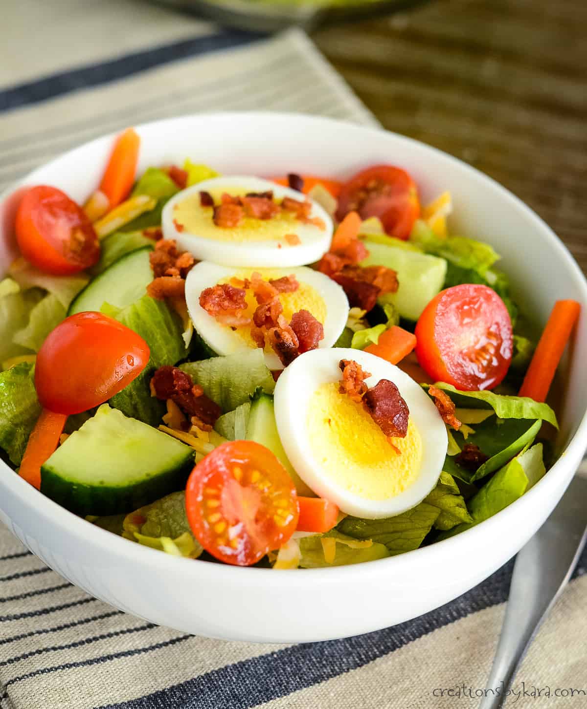 bowl of greens, vegetables, eggs, and bacon