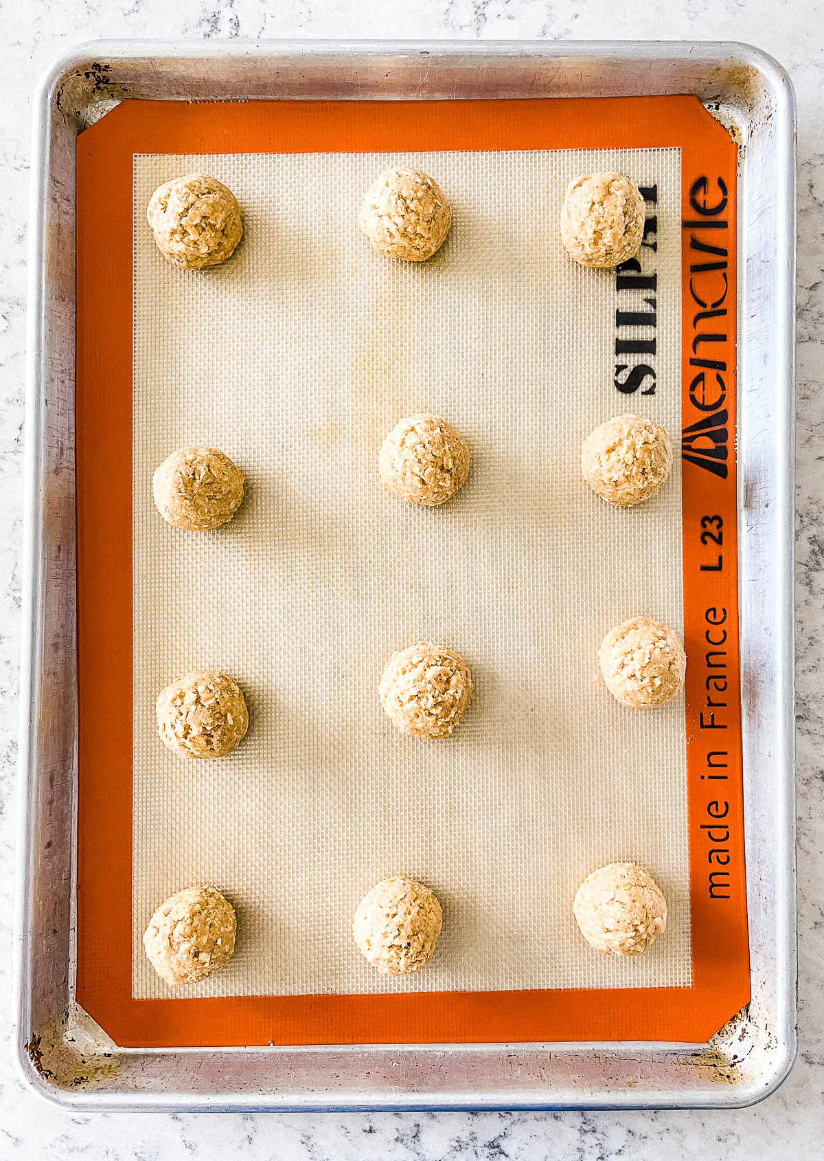 cookie dough balls on a silicone lined baking sheet