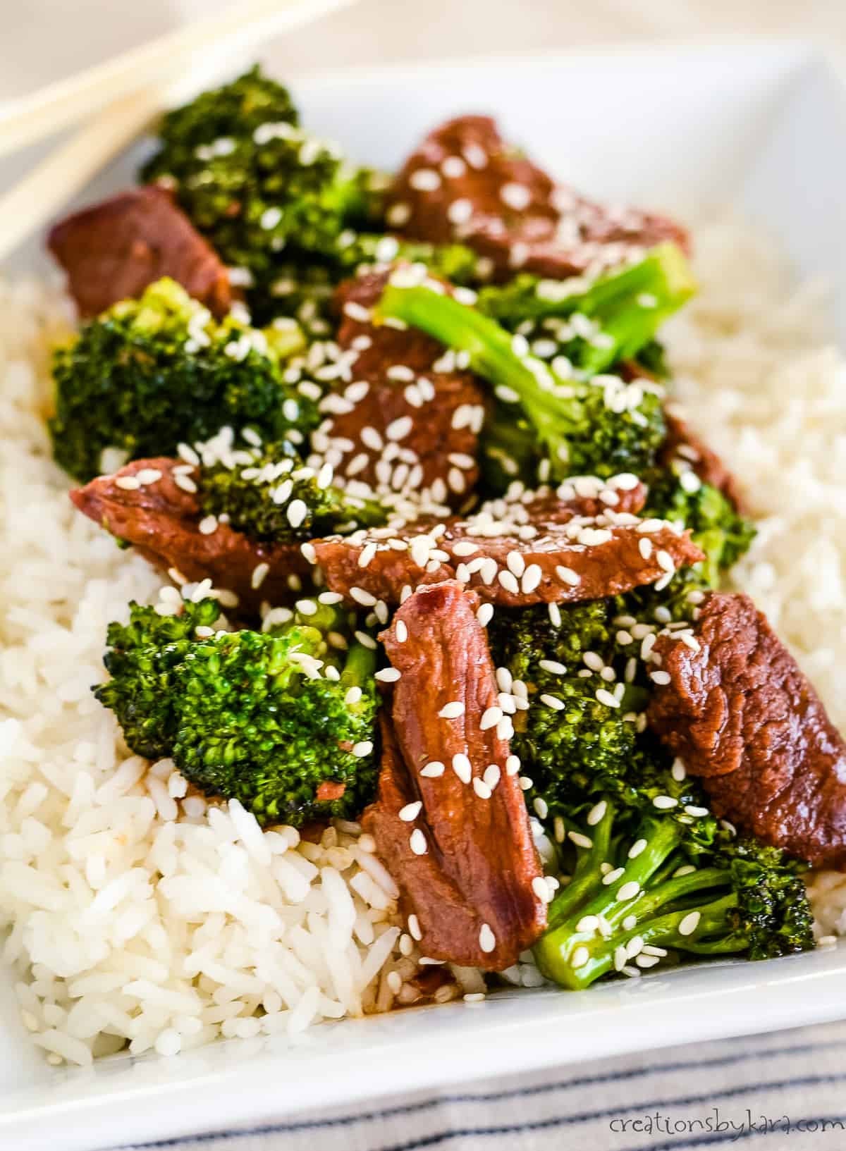beef with broccoli over rice, garnished with sesame seeds.